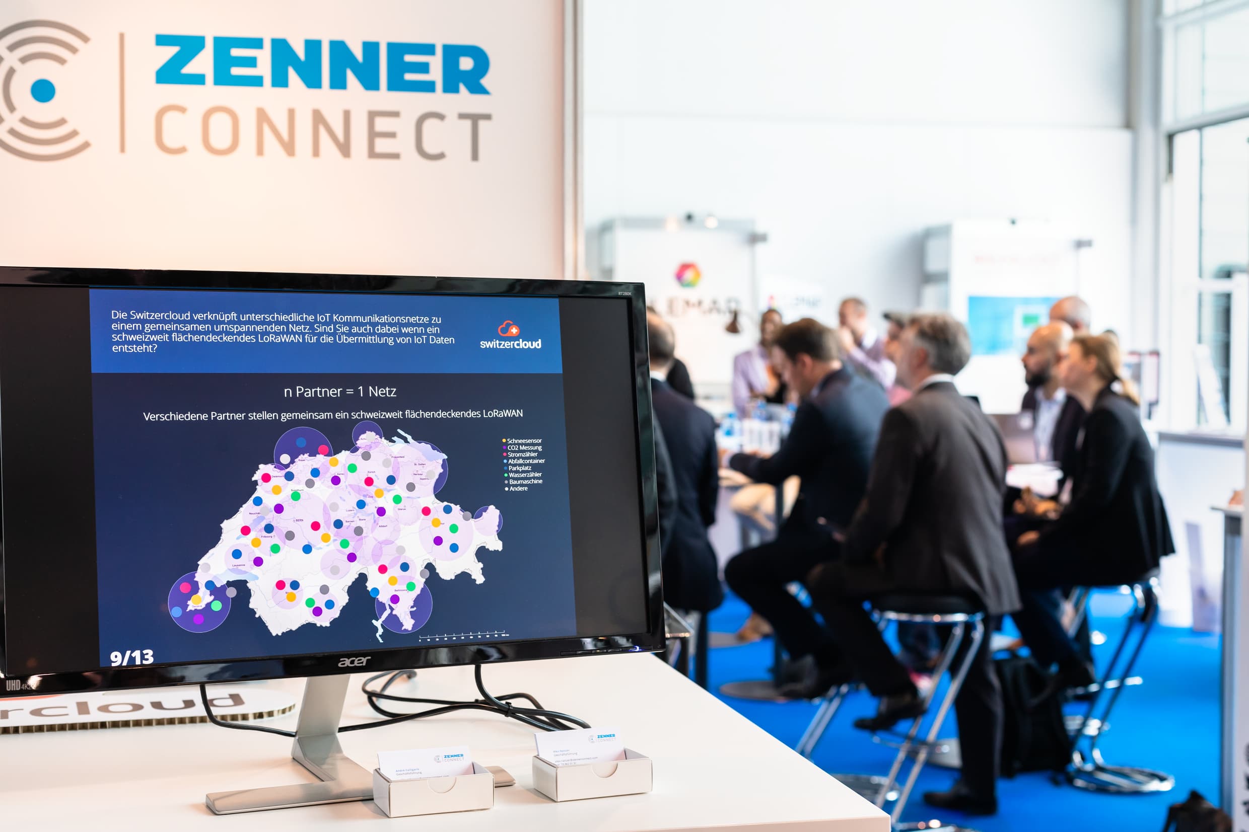 Monitor with Switzerland as a graphic on it; audience sitting on high chairs in the background.